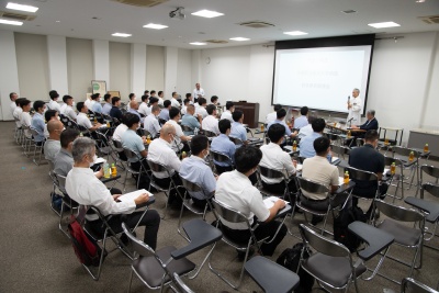 写真:勉強会の風景。大勢の人が講師の話を聞いている。