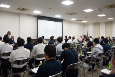 写真：勉強会の風景。大勢の人が講師の話を聞いている。